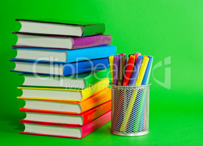 Stacks of colorful books and socket with felt pens