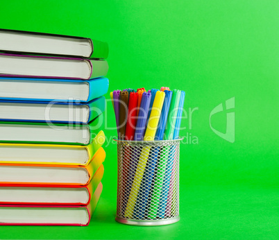 Stack of colorful books and socket with felt pens