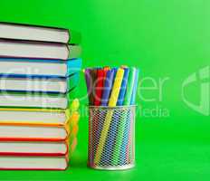 Stack of colorful books and socket with felt pens