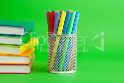 Stacks of colorful books and socket with felt pens