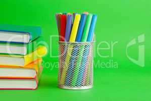 Stacks of colorful books and socket with felt pens