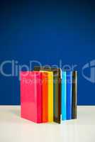 Row of colorful books and tablet PC over blue background