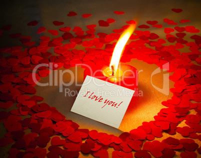 Burning heart shaped candle and a card