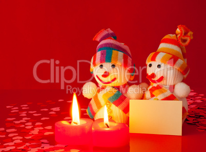 Three snowmen with two burning heart shaped candles