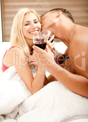 Man kissing and drinking on the bed