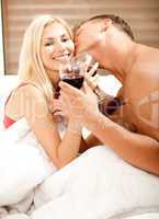 Man kissing and drinking on the bed