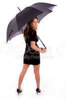 back pose of smiling female carrying umbrella