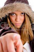 portrait of young female with winter coat pointing at camera