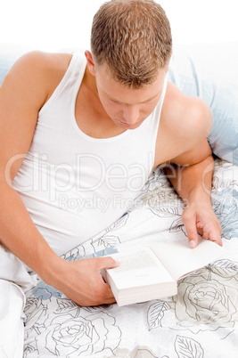 man lying on bed and reading book