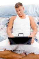 man working on laptop in bed