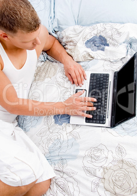 half length of laying man working on laptop