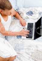 half length of laying man working on laptop