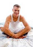 smiling young man sitting on bed and looking at camera