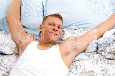 relaxing man stretching his arms in bed
