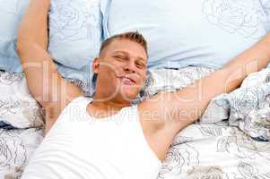 relaxing man stretching his arms in bed