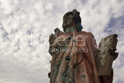 A grungy religious statue in teh middle of nowhere.