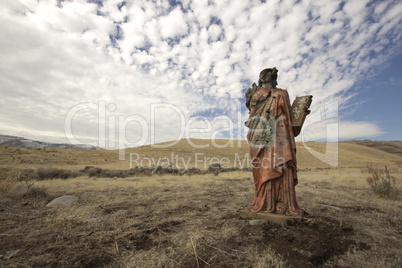 A grungy religious statue in teh middle of nowhere.