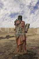 A grungy religious statue in teh middle of nowhere.