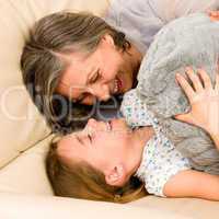 Grandmother with granddaughter hugging on sofa