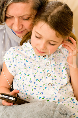 Grandmother and young girl listen music together