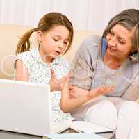 Grandmother and young girl with laptop learn count