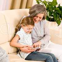 Grandmother with granddaughter use touch tablet