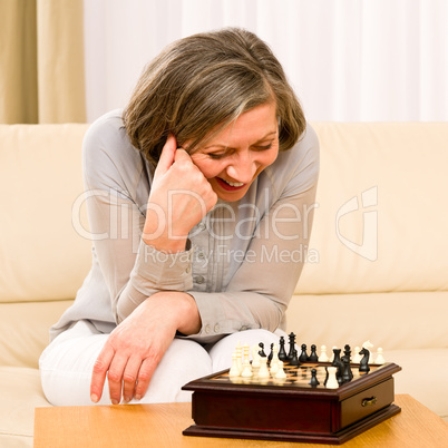 Senior woman play chess happy sit on sofa