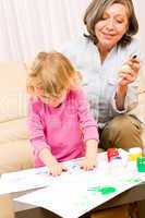 Little girl with grandmother play paint handprints