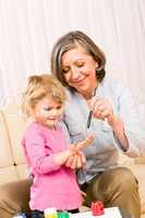 Little girl with grandmother play paint handprints