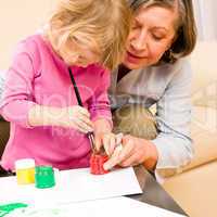 Little girl with grandmother play paint handprints