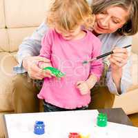 Little girl with grandmother play paint handprints