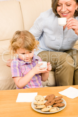 Little girl with grandmother eat cookies