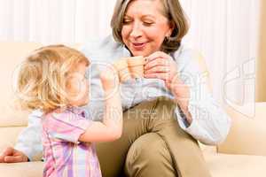 Grandmother with granddaughter drink tiny cups