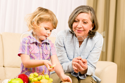 Grandmother with granddaughter eat fruit at home