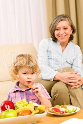 Little girl eat apricot fruit with grandmother