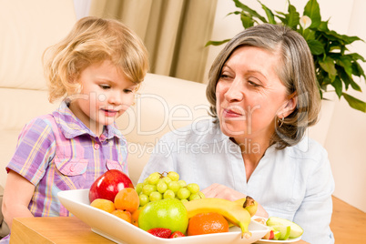 Grandmother with granddaughter eat fruit at home