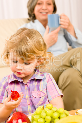 Little girl eat strawberry fruit with grandmother