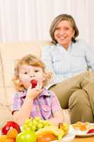 Little girl eat strawberry fruit with grandmother