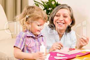 Little girl with grandmother play glue paper