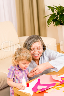 Little girl with grandmother play glue paper