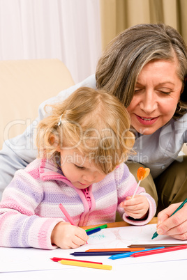 Cute little girl drawing with grandmother at home
