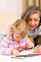 Cute little girl drawing with grandmother at home