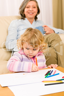 Grandmother and granddaughter drawing at home