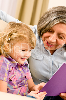 Grandmother and granddaughter read book together