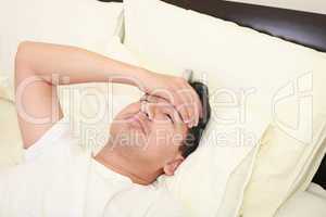 Close up of young man lying down in bed taking temperature and h