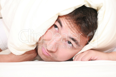 Man trying to sleep with a pillow over his head and close to wak