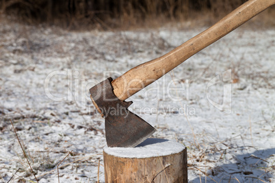 Axe and log in winter forest