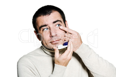 man inserting a contact lens in his eye