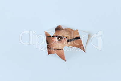 Mann mit Brille schaut durch ein Papierloch