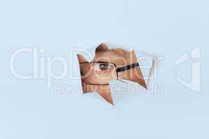 Mann mit Brille schaut durch ein Papierloch